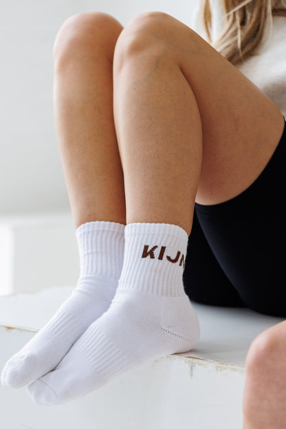 Neutral unaltered ribbed socks layered over fabric leggings