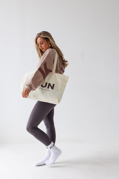 Neutral soft-touch tote bag styled with brown high waisted leggings